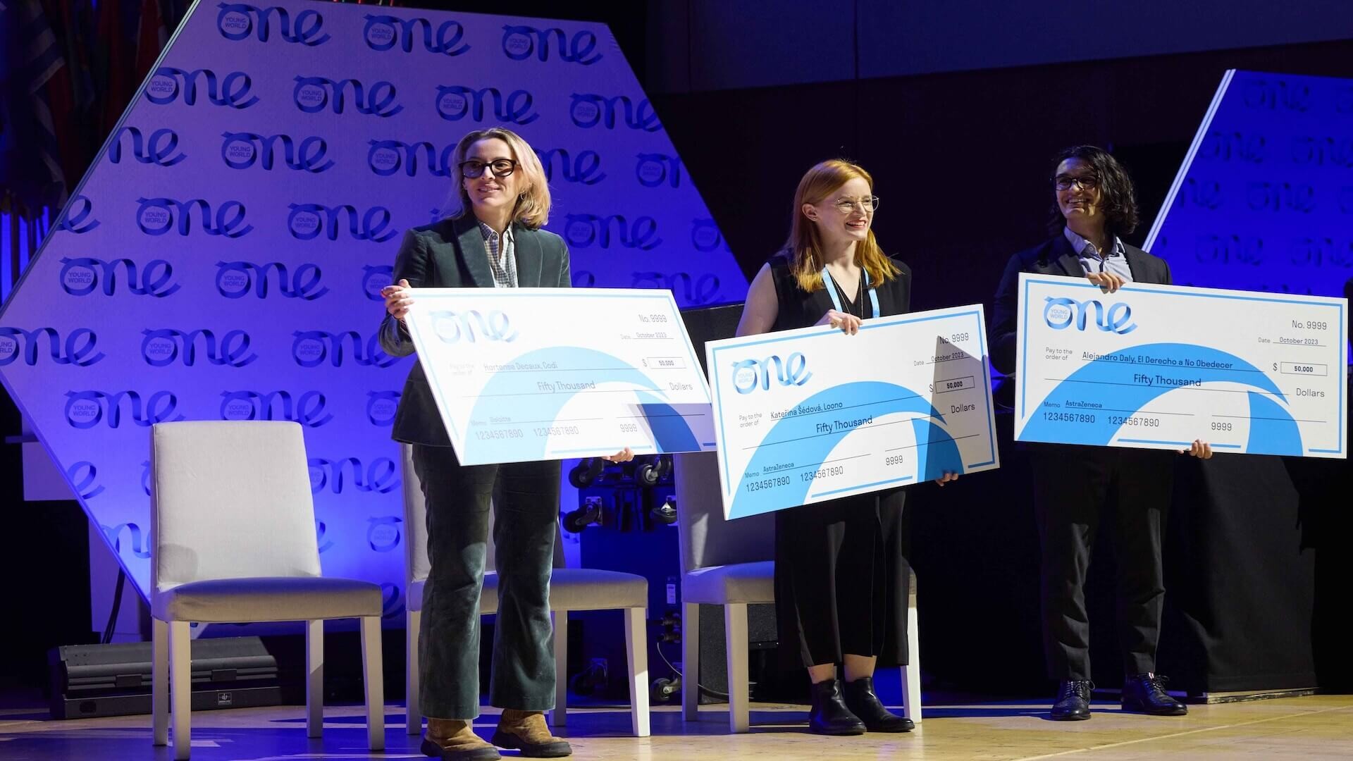 OYW Lead2030 Challenge Winners holding large branded cheques at the 2023 Summit presentation stage taking a group photo