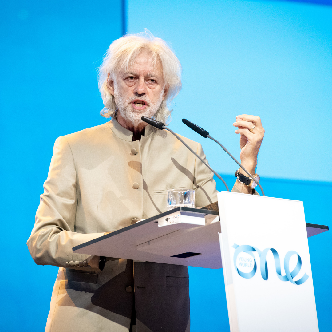 Bob Geldof mid-speech against a blue backdrop at the One Young World 2021 Opening Ceremony in Munich.