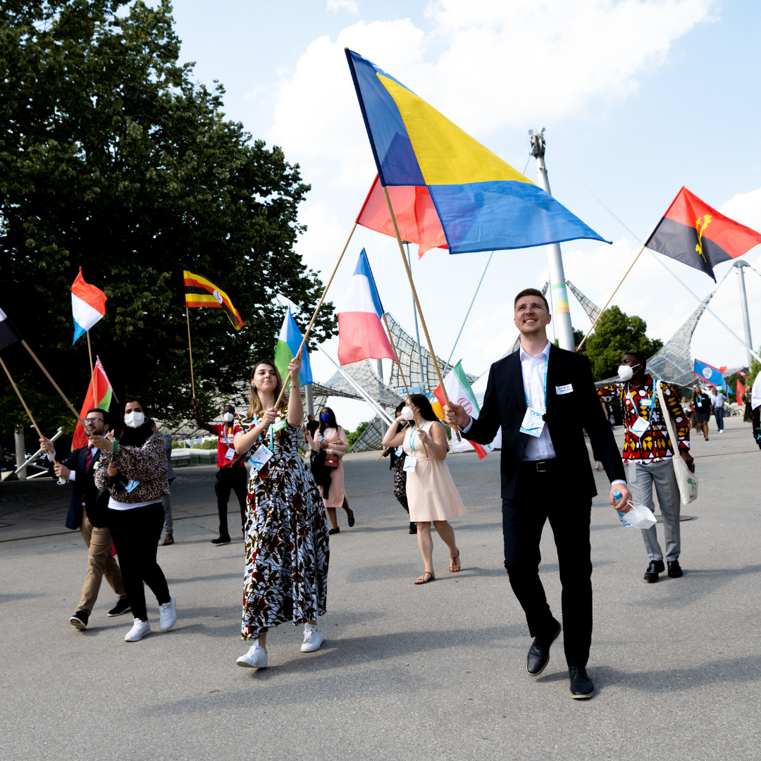One Young World Delegates carrying flags walk away from the Olympiahalle in Munich.
