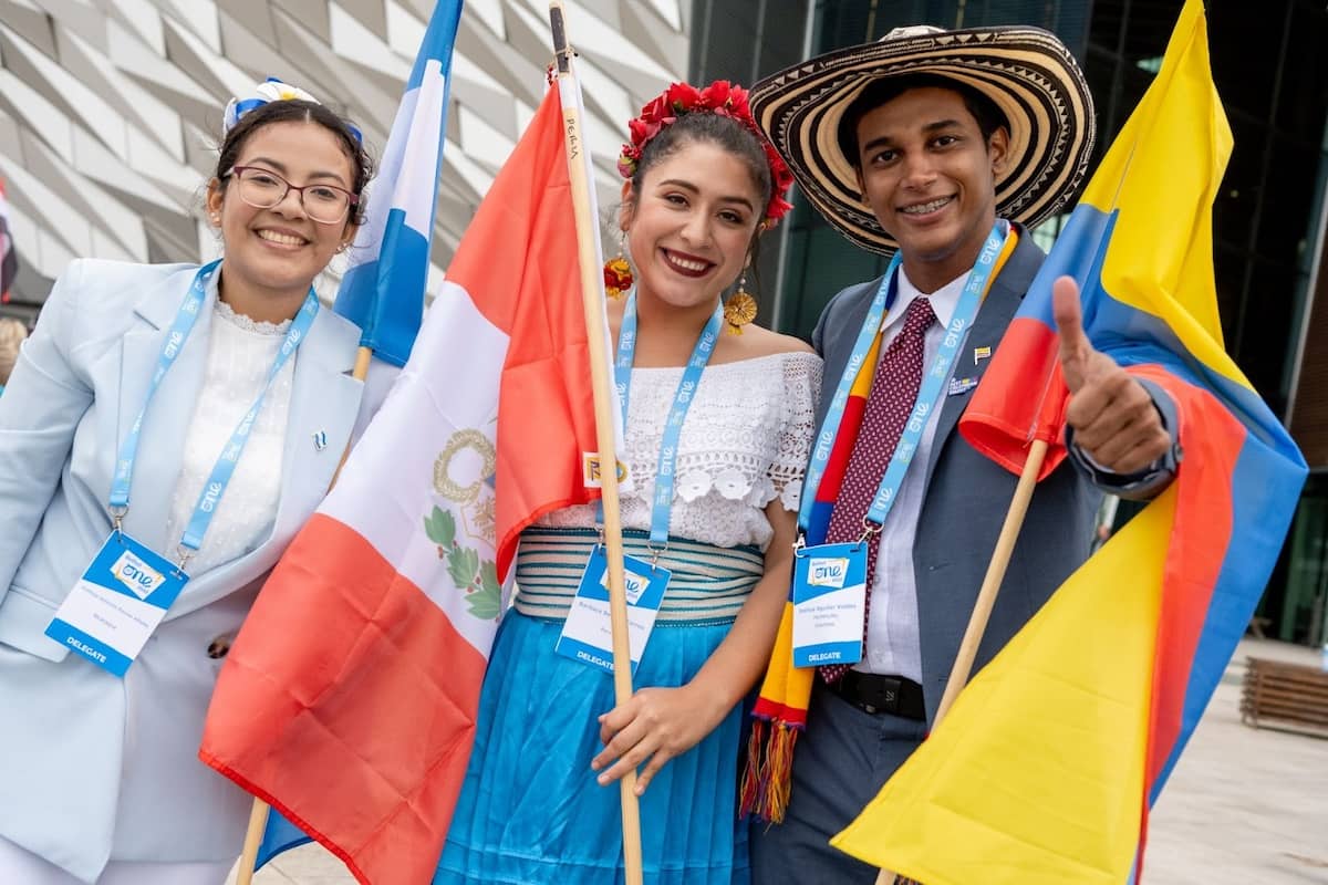 Delegates group photo holding national flags of Latin America for the Barranquilla Scholarship outside Titanic Belfast 2023