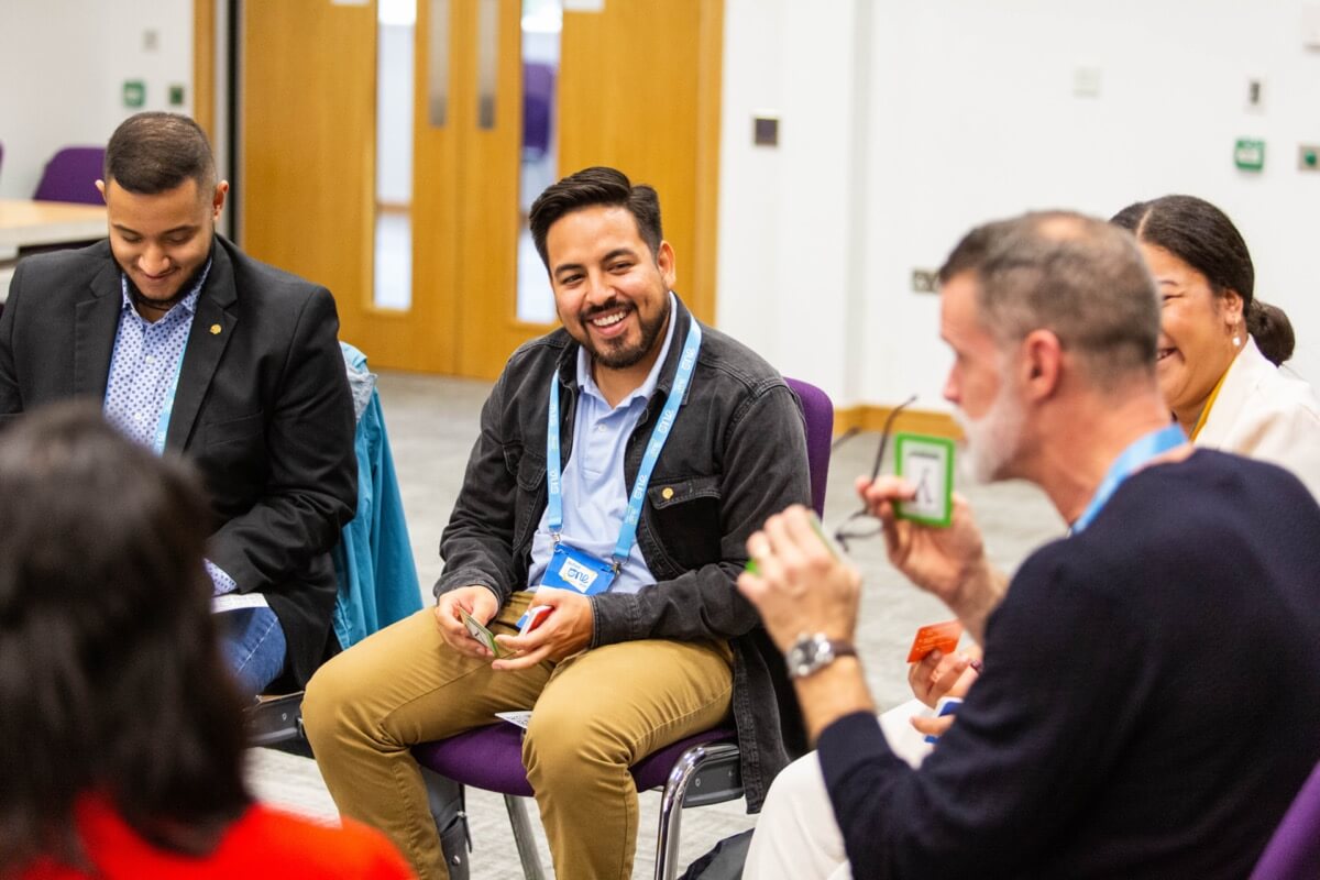 Cheerful group session of youth delegates conversing with Mark Tewksbury