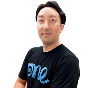 Portrait of Hiroshi Osamura wearing black tee shirt with One Young World Logo