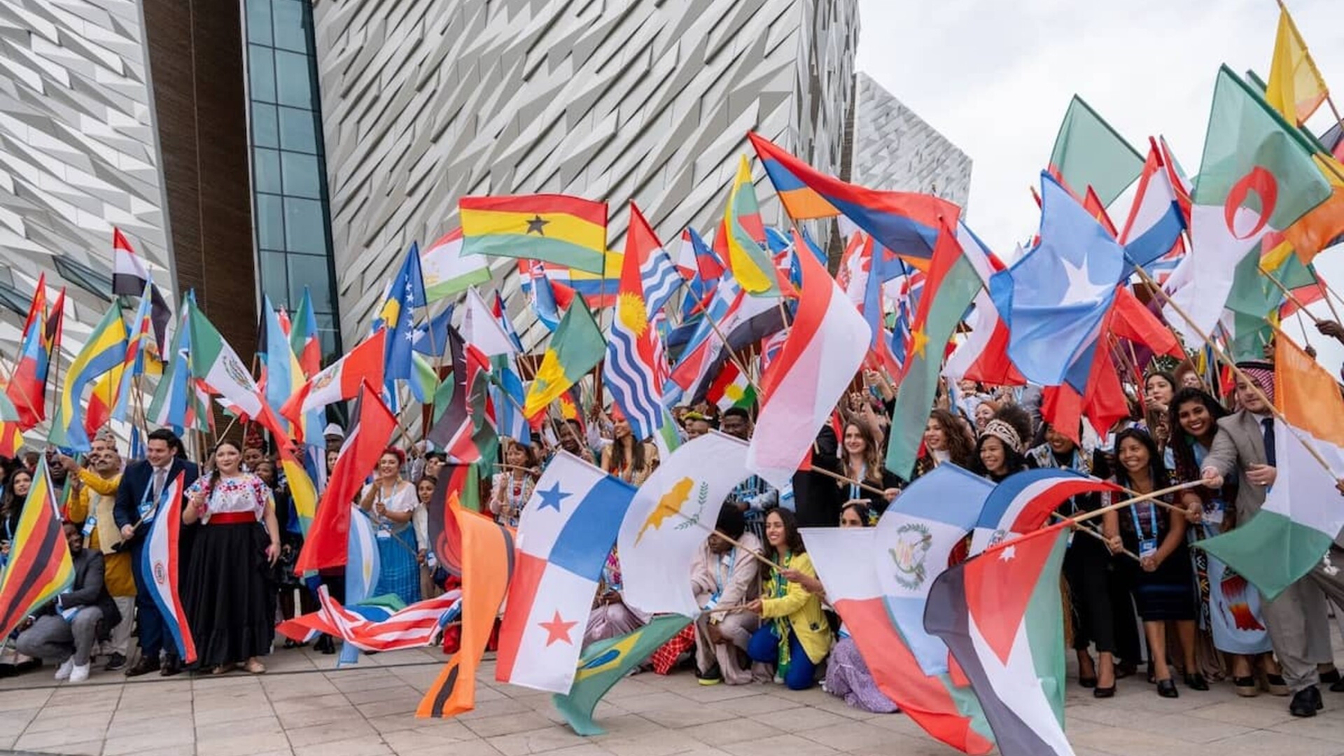 People waving national flags outside the Titanic Belfast Museum