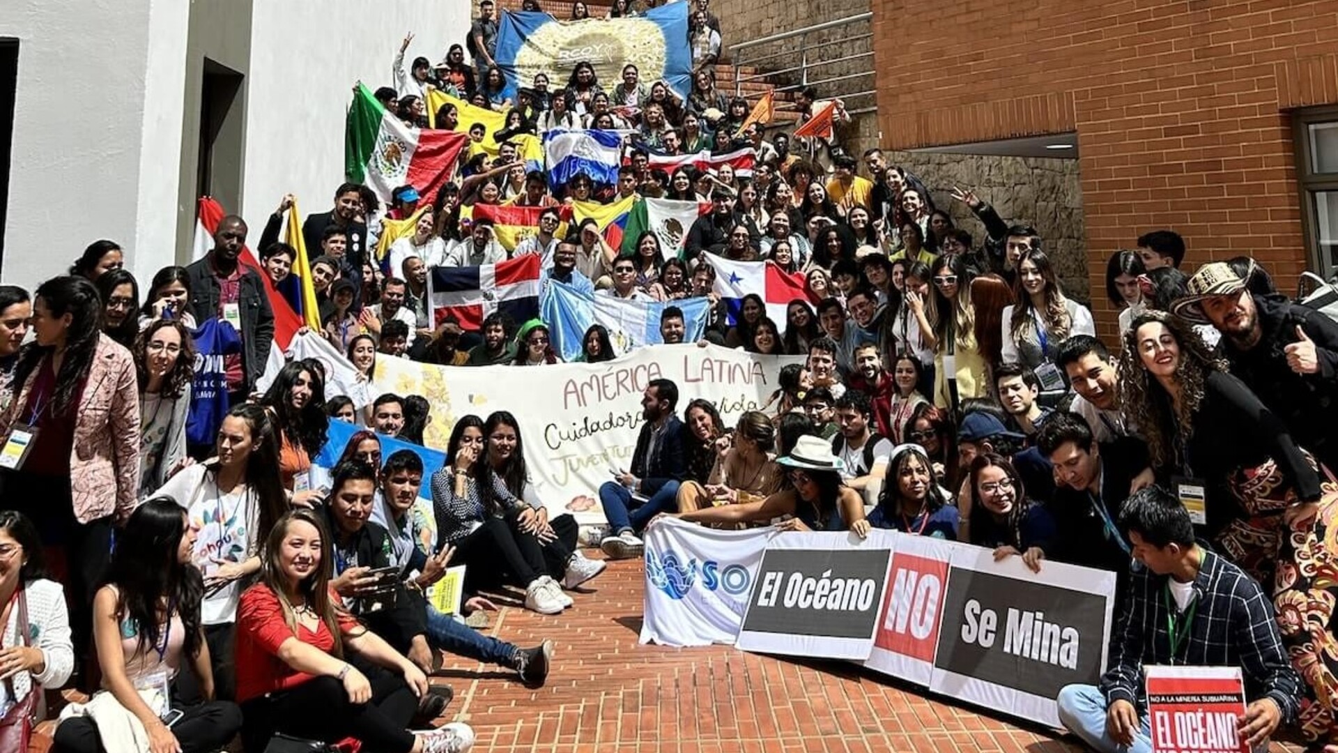 Latin America delegation holding banners and national flags in a large group photo