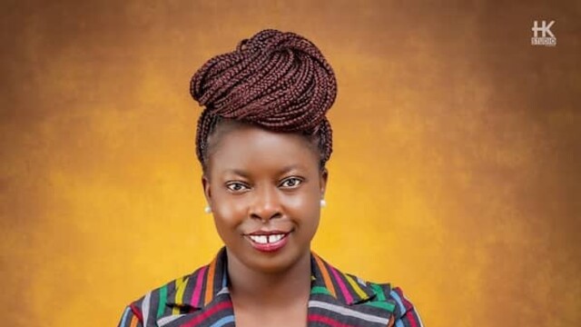 Portrait d'Adenike Oladosu portant une veste colorée à rayures sur fond brun jaune