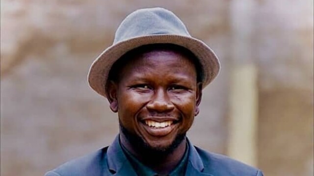 Elihu Jos Benam en blazer bleu foncé et chapeau