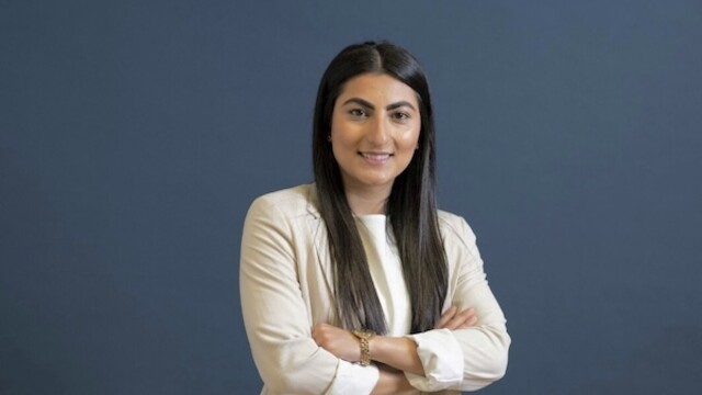 Photo de portrait de Farkhunda Muhtaj portant un long manteau beige sur fond bleu foncé
