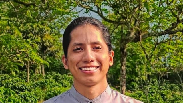 Johan Chavez en chemise blanche sur fond de buisson vert