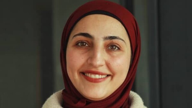 Lama Amro avec un foulard marron sur fond vert foncé