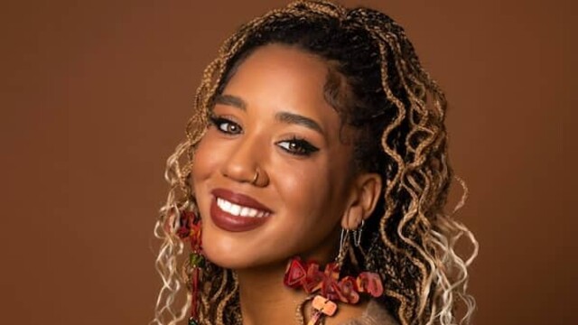 Portrait de Larissa Crawford portant un haut marron clair sur un fond marron plus foncé
