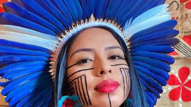 Maricelma Francelino Fialho Cândido portant un couvre-chef indigène et se maquillant le visage