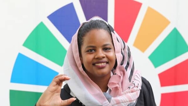 Photo de Nisreen Elsaim contre la roue des couleurs des ODD de l'ONU