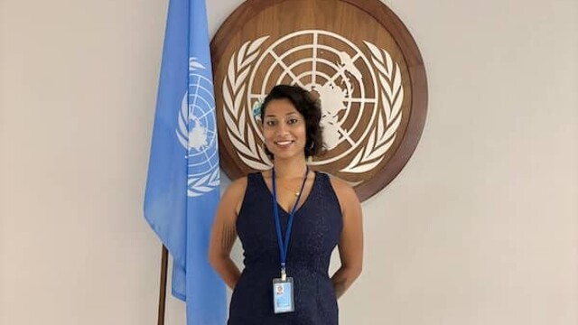 Serena Bashal posing next to the UN flag