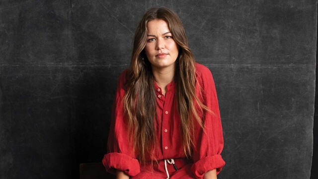 Portrait de Vanessa Turnbull-Roberts en robe rouge assise sur fond noir