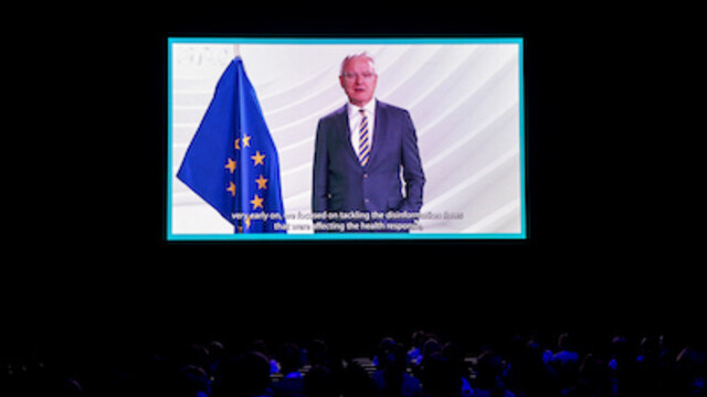 Peter Wagner in navy blue suit and stripe tie presenting his key note on Disinformation  with an EU flag in background