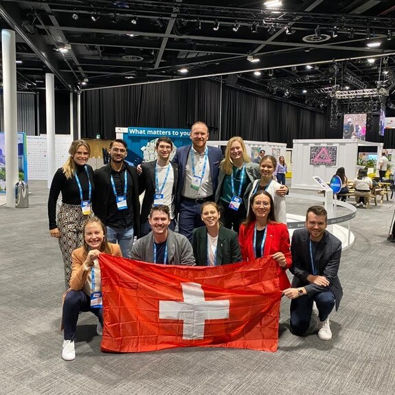 Delegates at Belfast 2023 summit holding Swiss National Flag