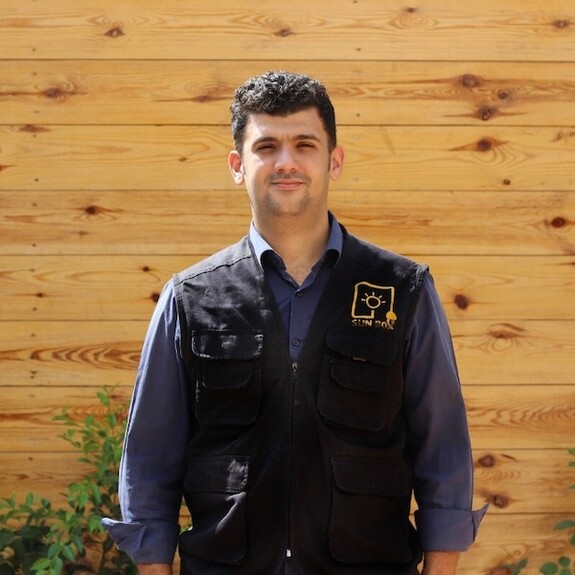 Mohammed Mashharawi wearing dark blue jacket against wood panel background