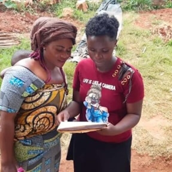 Rebecca Aime sharing a document with a middle aged mother with headress and colourful outfit