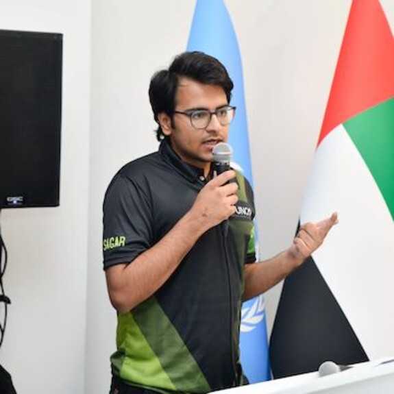 Sagar Kalra in black and shaded green t-shirt presenting at COP28