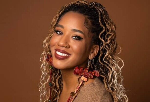 Portrait de Larissa Crawford portant un haut marron clair sur un fond marron plus foncé