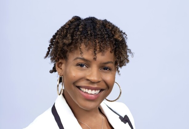 Lashyra Nolen in white overcoat blazer against light blue background