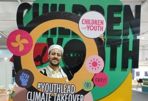 Saad Uakkas holding up a youth-lead Climate Takeover signage
