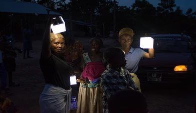 A group of women hold solar lights