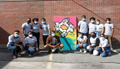 a group of people in medical masks stands in front of a mural