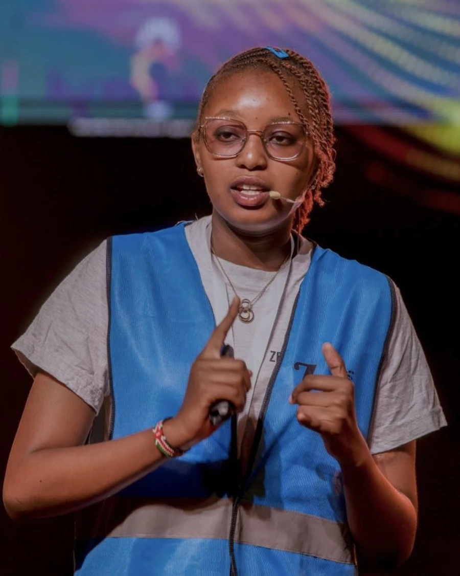 Norah Kimathi wearing blue high-vis jacket presenting on stage