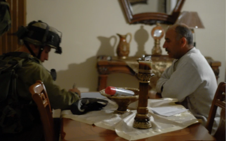men sitting at table, one military taking notes