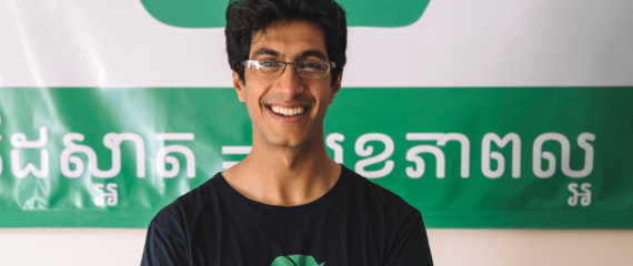 Samir Lakhani smiling in front of an Eco-Soap Bank sign