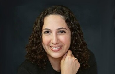 Ariane portrait, wearing black blazer against dark grey black background