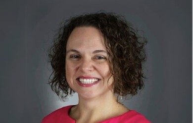 Gabriela portrait, wearing red pink dress against grey background