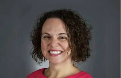 Gabriela portrait, wearing red pink dress against grey background