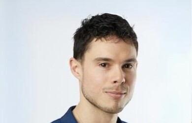 Nick portrait wearing white undershirt with navy blue blazer against white background