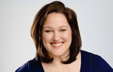 Sarah portrait wearing navy blue top against grey background