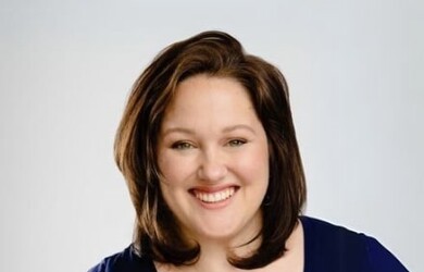 Sarah portrait wearing navy blue top against grey background