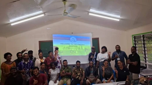 A group of new ENB Sea Keepers volunteers stand around a powerpoint presentation