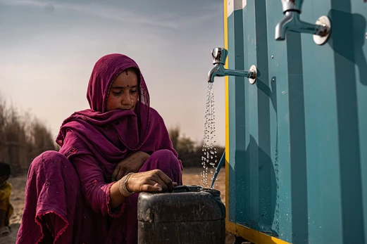 a woman gathers water at an OASIS box