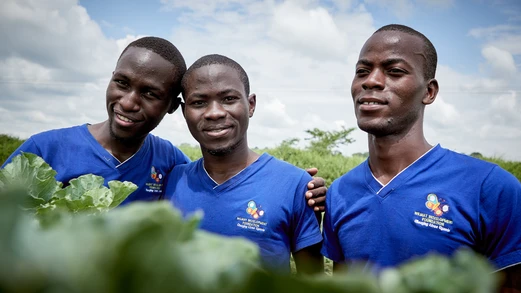 group of three ugandan men stand in garden