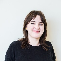 Photo of Megan Thomas wearing black jumper and pants against white background