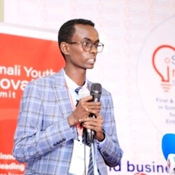 Abdikadir Ali Ibrahim public speaking wearing checkered light blue blazer