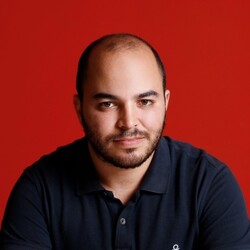 Portrait of Achref Mattar in black polo against red background