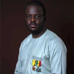 Mohamed Doumbia portrait in white linen shirt with breast medals