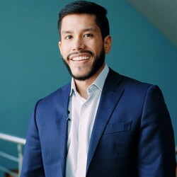 Federico Perez in navy blue suit jacket and white shirt with light blue background