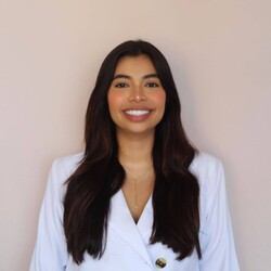 Portrait of María José Charris Vizcaíno in white siuit against beige background