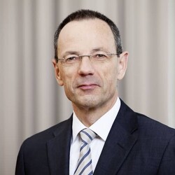 Portrait of Dr. Lino Guzzella in formal attire against striped beige background