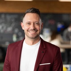 Marc Maurer wearing white undershirt and maroon blazer against blurred indoor room background